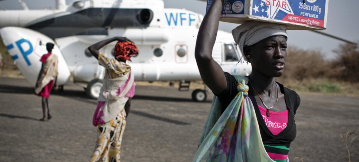 Women carry emergency food supplies from a World Food Programme (WFP) helicopter that landed in Thanyang, South Sudan.