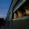 En Macedonia, tres niños miran por la ventana de un tren, que traslada a refugiados de Siria, Afganistán e Iraq a un centro de recepción para migrantes y refugiados. Foto: UNICEF / Ashley Gilbertson