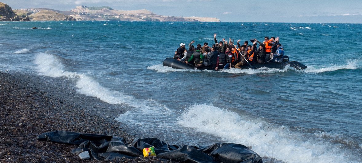 Des réfugiés rient et saluent alors que le zodiac dans lequel ils se trouvent s’approche du rivage, près du village de Skala Eressos, sur l’île de Lesbos, en Grèce.