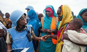 La agente de la Misión de la ONU en Darfur, Grace Ngassa, de Tanzania, y la voluntaria de vigilancia comunitaria Jazira Ahmad Mohammad hablan con mujeres del campo para desplazados internos de Zam Zam, en Darfur del Norte. 