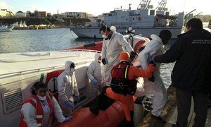 Des garde-côtes italiens débarquent sur le quai de l'île de Lampedusa des survivants d'une tragédie en mer en Méditerranée, en février 2015.