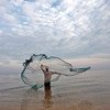 Рыбак забрасывает сеть в воды Тиморского моря