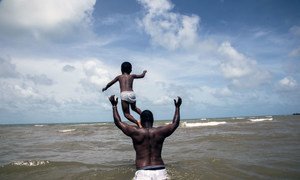 A four-year-old boy and his father Marshall Mejia, play in the water during a visit to the seashore, in their hometown of Dangriga, on the south-eastern coast of Belize.