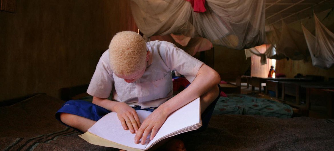 一名白化病儿童在一所小学读盲文。