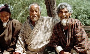 Elderly Bhutanese men commune with each other on a park bench.