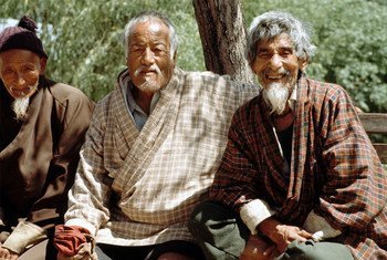 Elderly Bhutanese men commune with each other on a park bench.