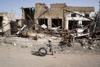 也门萨达老城，一名男童滚着轮胎从已成废墟的房屋跟前经过。