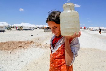 In the makeshift camp at Ain Issa a 12-year-old girl carries a jerrycan of water. She arrived with her family after a three-day journey from war-torn Raqqa. UNICEF/Souleiman