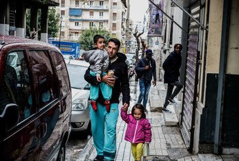 一名阿富汗难民带着自己的两个孩子从希腊雅典一家难民学习中心门外经过。