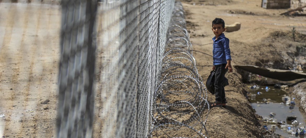 A young boy stands next to a fence surrounding the football pitch at Al-Shuhadaa Stadium in the city of Iskandariya, Babil Governorate, Iraq. UNICEF/Khuzaie