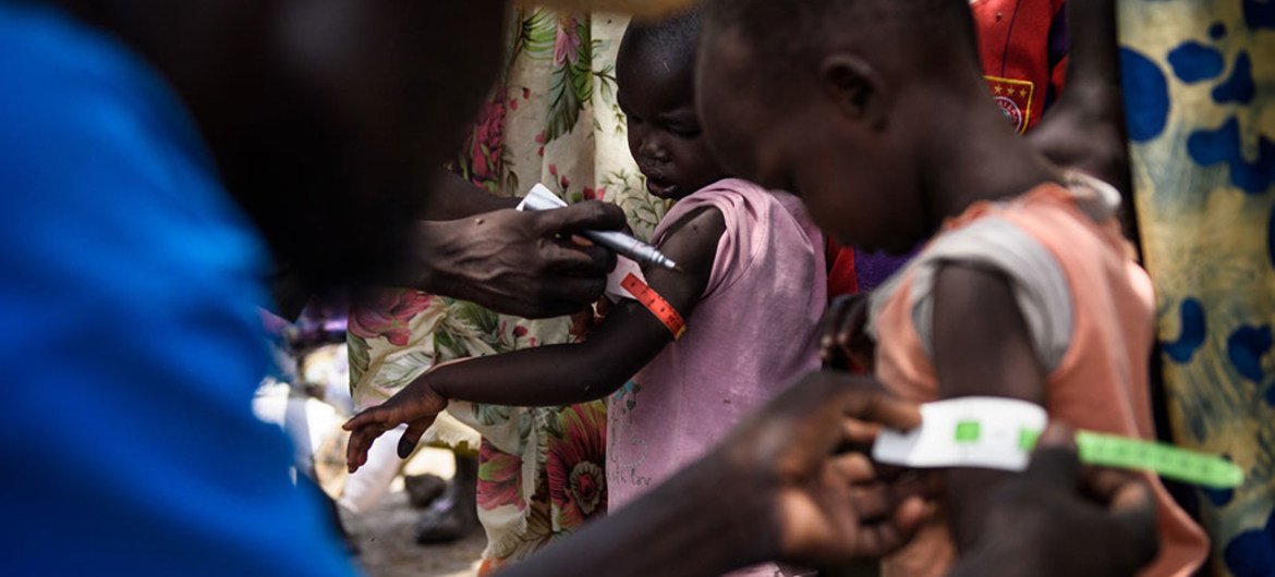 A UNICEF nutrition volunteer measures the mid-upper arm circumference (MUAC) of a child during a health screening as part of a UNICEF Rapid Response Mission to the village of Aburoc, South Sudan.