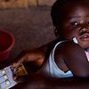 A two-year-old girl is held by her mother as she is prescribed a course of medication to treat malaria at a community clinic in rural Kasungu district, Malawi.
