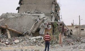Une personne de dos au milieu de bâtiments détruits et de décombres dans la ville de Tabqa, dans le gouvernorat de Raqqa, en Syrie.