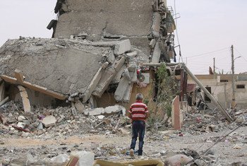 A person walks amid destroyed buildings and rubble in Tabqa city, Raqqa governorate, Syria.