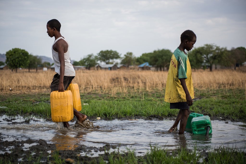 Two boys, 16 and 12 years old , collect water from a damaged pipe on the outskirts of Juba, South Sudan. The water is pumped from the White Nile River, but is untreated, risking the health of those who consume it.