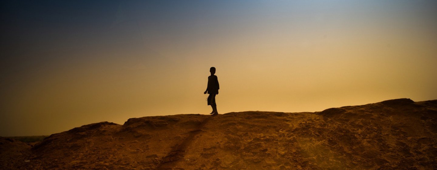A boy walks on a sand bank surrounding a refugee camp in M'bera, Mauritania.