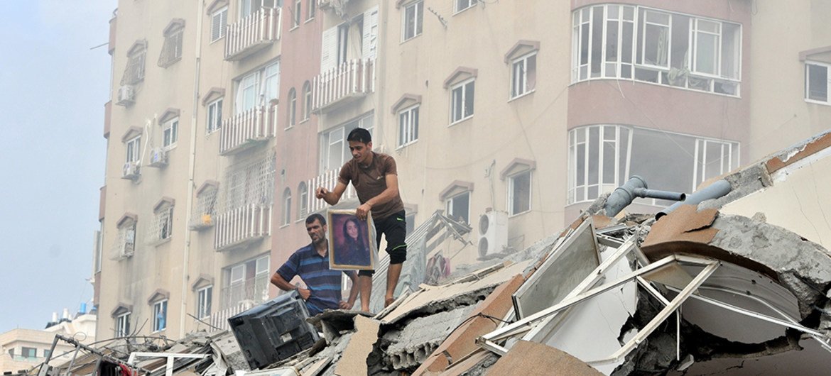 Palestinos recoben sus pertenencias entre los escombros de una torre residencial destruida durante un bombardeo israelí el 24 de agosto de 2014.