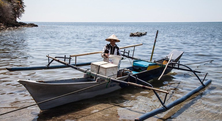 Рыбак выгружает свою традиционную рыбацкую лодку на севере Сулавеси, Индонезия.