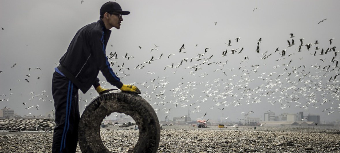 First prize winning photo portrays a volunteer removing a tire from a beach in Lima, Peru, taken by Nicolas Monteverde Bustamante of Universidad Peruana de Ciencias Aplicadas, Lima, Peru.