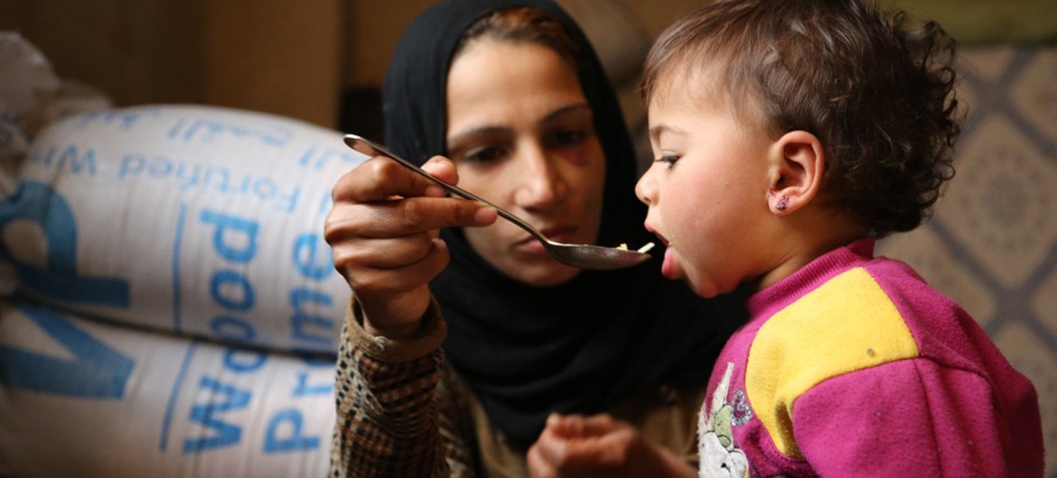 A mother, displaced with her family, feeds her 18-month-old daughter at a shelter in a village rural Damascus. (file)