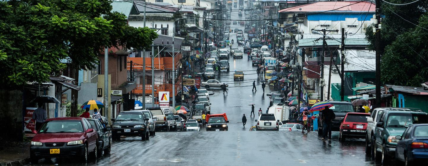 Une rue mouillée à Monrovia, au Libéria, avec des voitures et des piétons sous un ciel couvert.