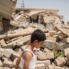 一名男孩路过伊拉克摩苏尔西部附近一出被战争摧毁的房屋建筑。