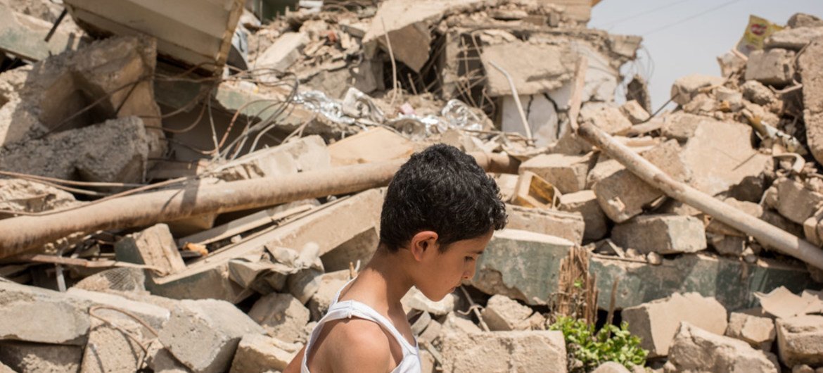 一名男孩路过伊拉克摩苏尔西部附近一处被战争摧毁的房屋建筑。