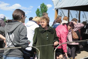 Un grupo de personas esperan en la fila para cruzar la línea divisoria en Marinka, en el este de Ucrania. 