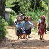 Watoto wakikimbia kwenye njia ya vumbi katika mazingira ya kijijini.