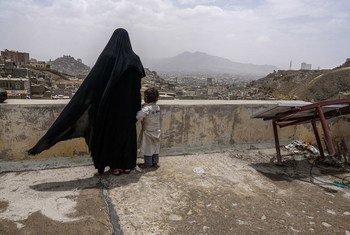 An internally displaced woman and her daughter look over the city of Sana’a, Yemen, from the roof of this dilapidated building they call their new home.