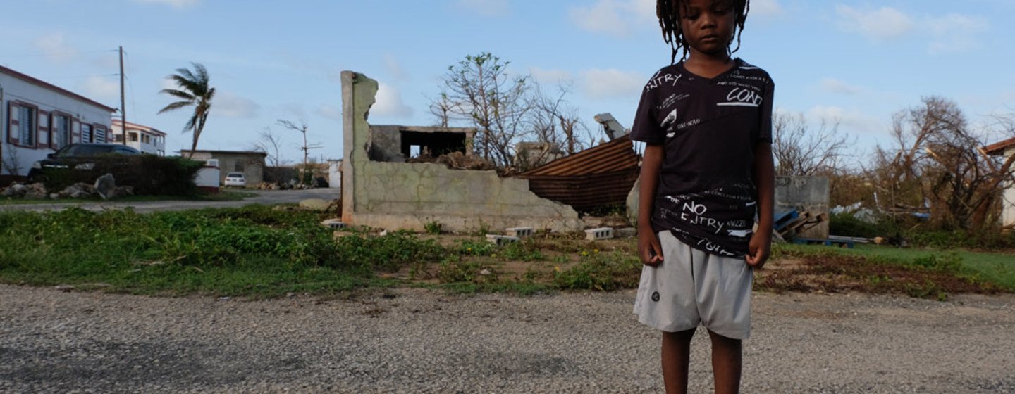 Un enfant de cinq ans devant des bâtiments partiellement détruits sur l'île d'Anguilla durement touchée par l'ouragan Irma en 2017.