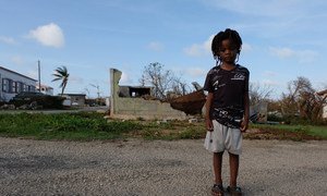 Un enfant de cinq ans devant des bâtiments partiellement détruits sur l'île d'Anguilla qui a été durement touchée par l'ouragan Irma. Septembre 2017.