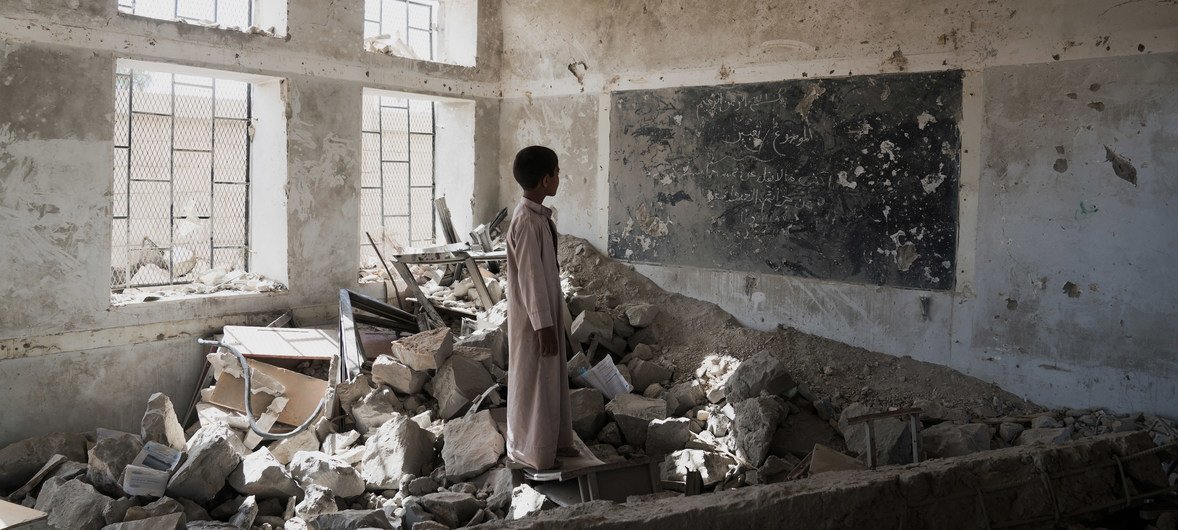 一名学生伫立在已成瓦砾的昔日课堂中。这座位于也门萨达的学校在2015年6月遭到损毁，目前学生正在附近的儿基会帐篷里上课。