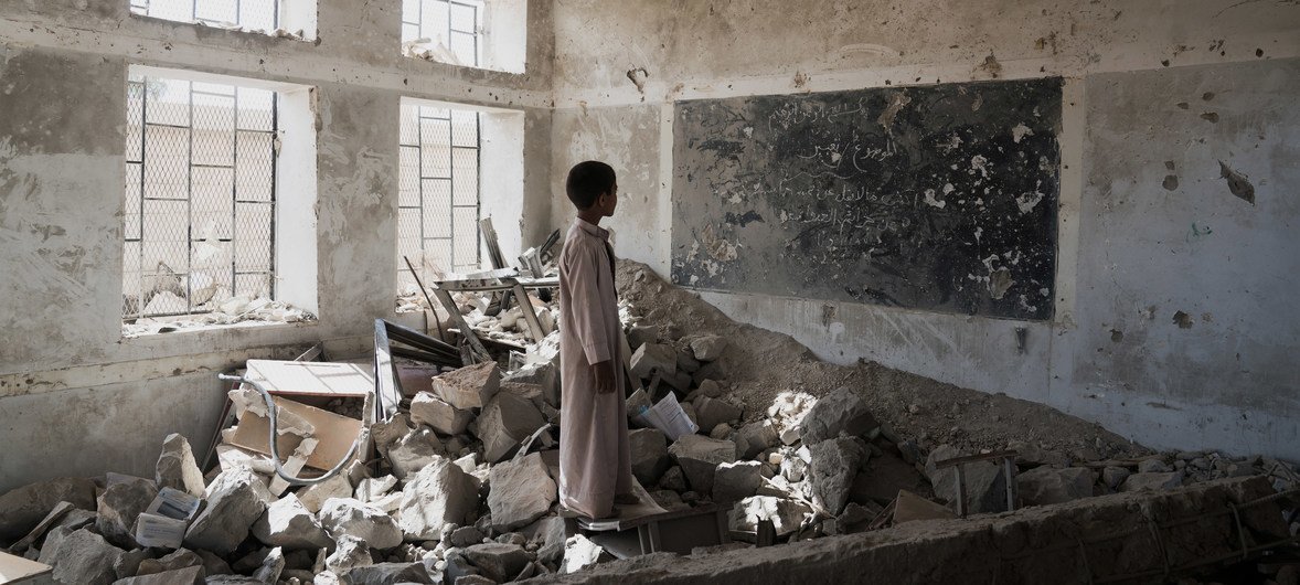 Estudante observa ruínas de sala de aula em escola destruída no Iêmen. Agora, os estudantes frequentam as aulas em uma tenda do Unicef