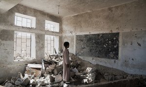 Estudante observa ruínas de sala de aula em escola destruída no Iêmen. Agora, os estudantes frequentam as aulas em uma tenda do Unicef