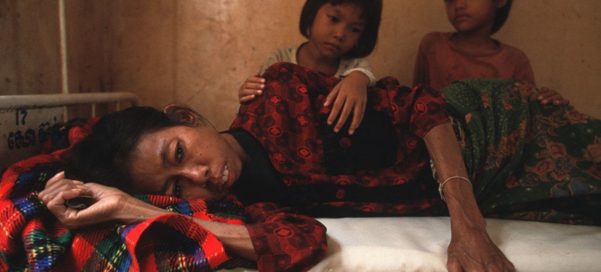 Two daughters look at their mother who is dying from HIV/AIDS. Cambodia. 2002.