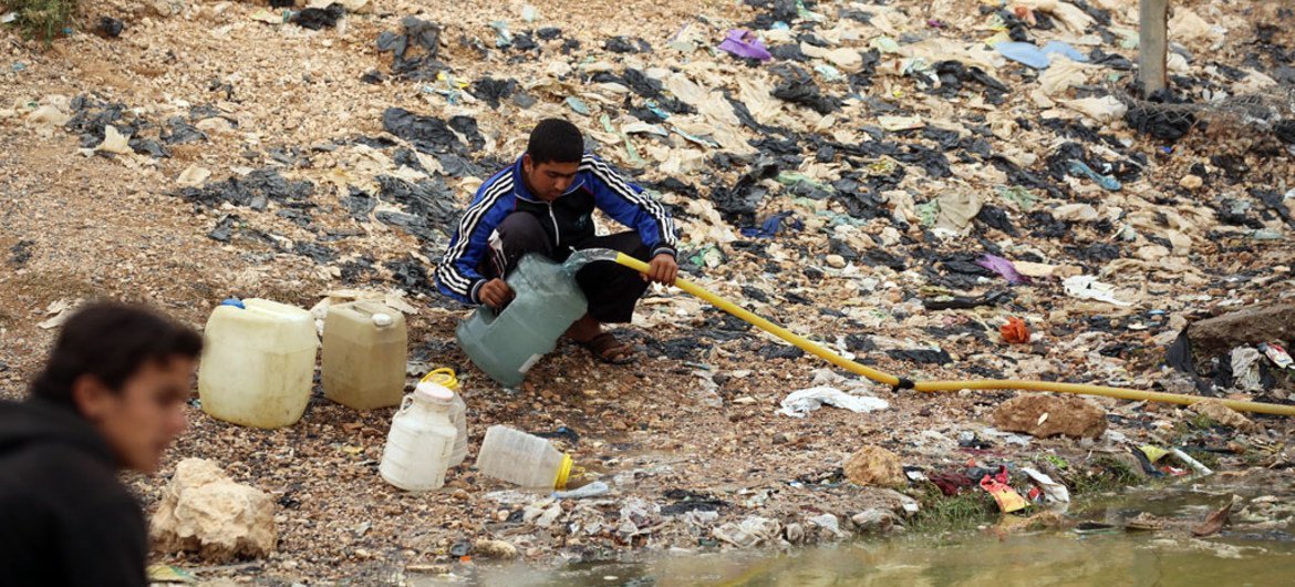 (من الأرشيف) أطفال يملأون أوعيتهم ماء ملوثا - مدينة الطبقة - شمال سوريا
