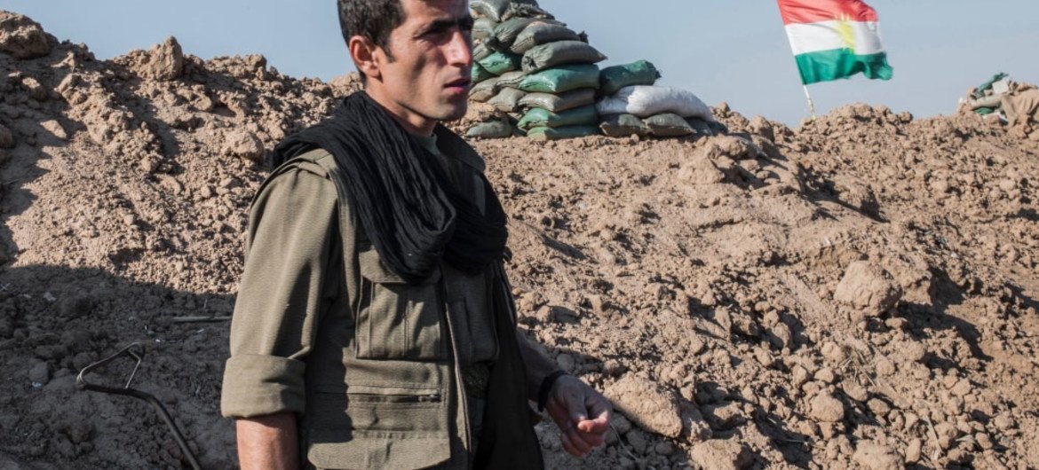 A Kurdish fighter on a frontline in Kirkuk province, northern Iraq, is 300 metres away from an Islamic State position. The flag of Kurdistan is behind him.