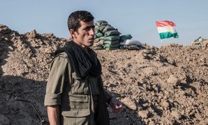 Un combattant kurde dans la province de Kirkouk, dans le nord de l'Iraq. Le drapeau du Kurdistan flotte derrière lui.