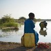 A young girl sits on a jerry can, as her mother fills up another with water, near the town of Jowhar, Somalia.