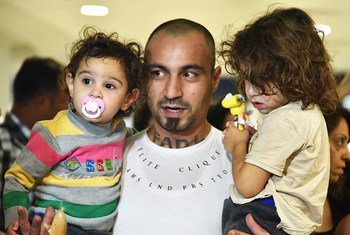 Un padre sirio cargando a sus dos hijos a su llegada al aeropuerto internacional de Santigo de Chile.