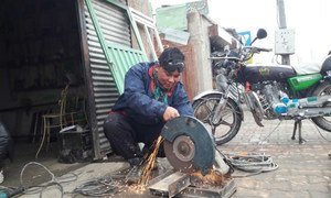Hassan Hosseini working in a metal workshop that he partially owns, due to assistance from UN migration agency (IOM) offices in Greece and Afghanistan.