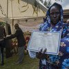 A woman in a blue floral shawl holds a certificate at the launch of the Refugee Vital Events Registration ceremony in Addis Ababa, Ethiopia, in October 2017.