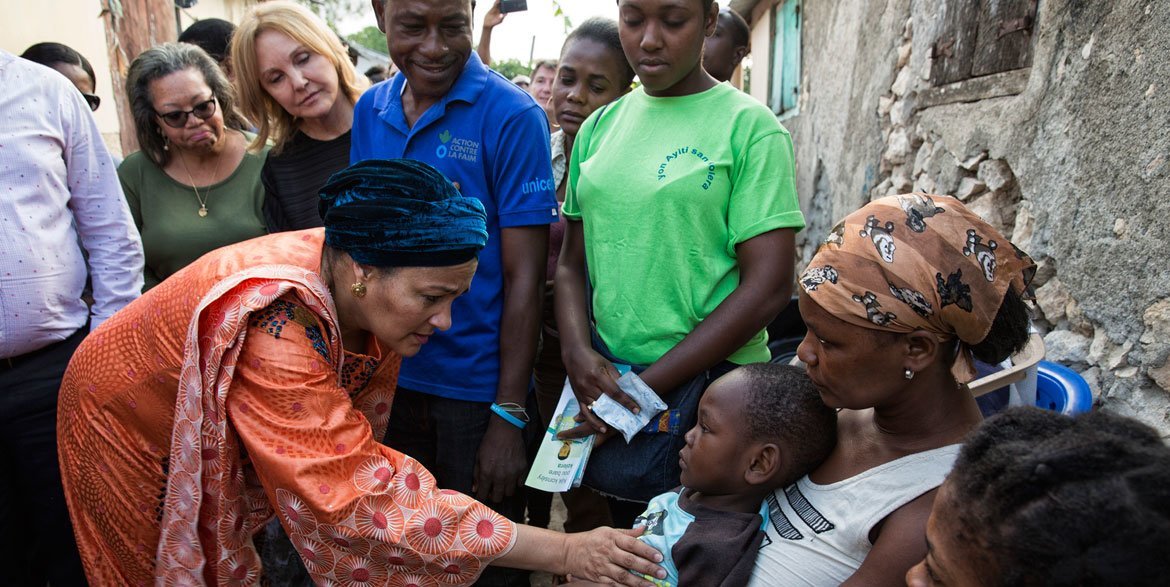 La Vice-Secrétaire générale de l'ONU, Amina Mohammed (à gauche) et l'Envoyée spéciale des Nations Unies pour Haïti, Josette Sheeran (à l'arrière plan gauche), avec des familles haïtiennes touchées par le choléra.