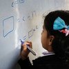 इराक़ के दोहुक में अपनी कक्षा में बोर्ड पर लिखती एक बच्ची.