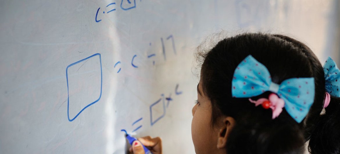 A young girl writes on a whiteboard during class at a school in Dohuk governorate, Iraq.