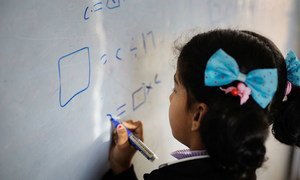 A young girl writes on a whiteboard during class at a school in Dohuk governorate, Iraq.