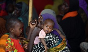A mother waits with her children to receive food at an Internally Displaced Persons camp at Doolow, Gedo region, Somalia (June 2017).