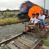 A train passing a ‘trolley’ - a makeshift rail cart made with wood or bamboo - in Manila, the Philippines.