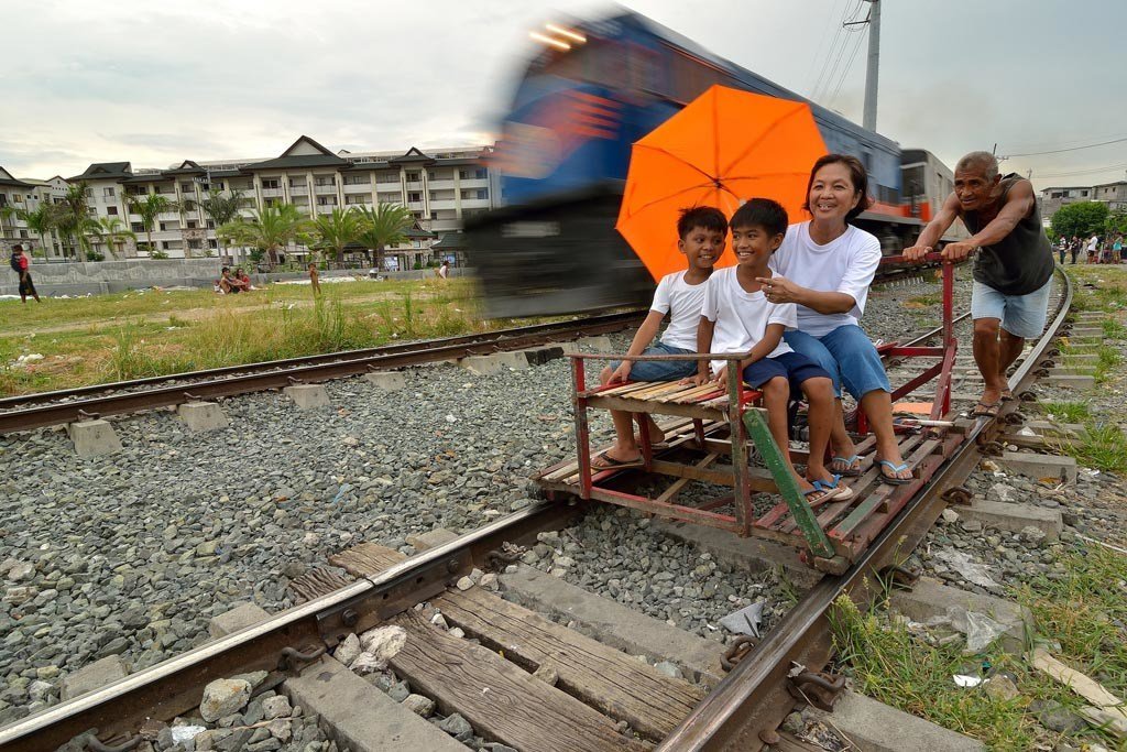 A train passes a ‘trolley’ – a makeshift rail cart made with wood or bamboo, popular with locals for transport – in Manila, the capital of the Philippines.